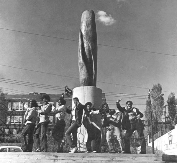 a group of young people posing in fron tof a sculpture in 1979.