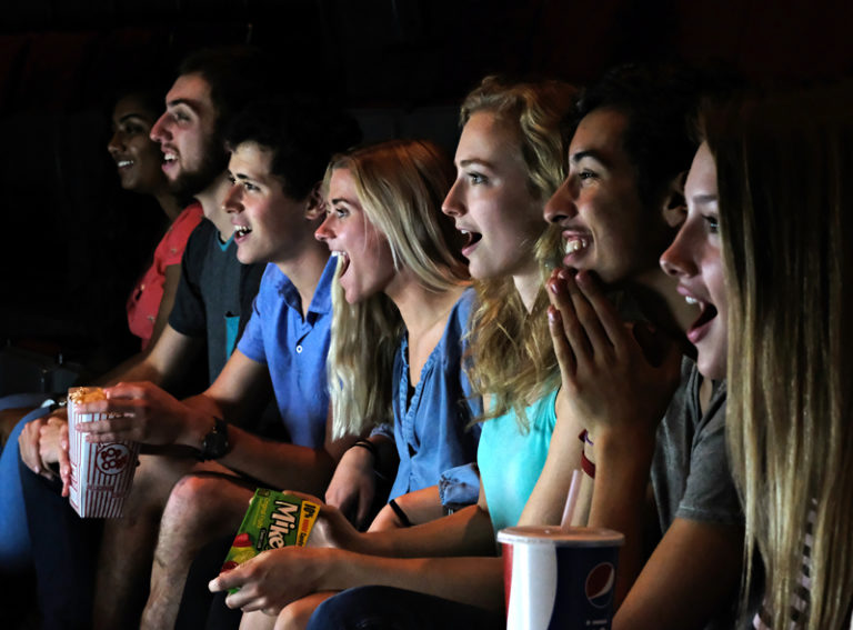 group of teens looking at movie screen in awe