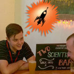 Two scientists talking to a man. THe scientists have cartoon thought bubbles above their heads depicting a rocket ship and a beaker.