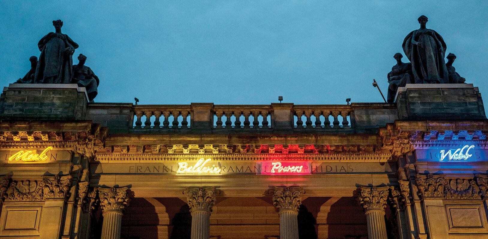An exterior view of the museum showing the neon names that wrap around the perimeter.
