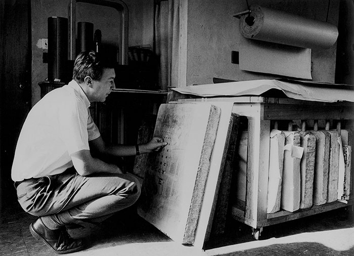 Black and white photo of artist jasper johns looking at artwork.