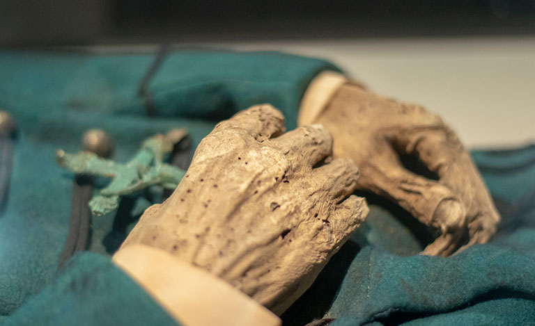 A detail of a mummified hand holding a crucifix.