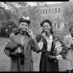 A black and white photo of two African-American girls eating candy apples.
