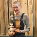 Hanna Dausch holding some of her wood artwork pieces
