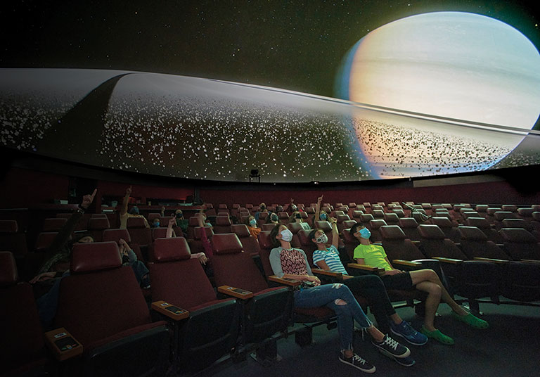 A photo of the audience in a theater looking up at the screen.