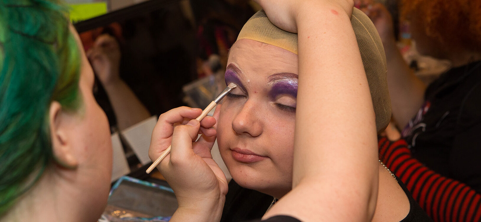 A teen having make-up applied to her face.