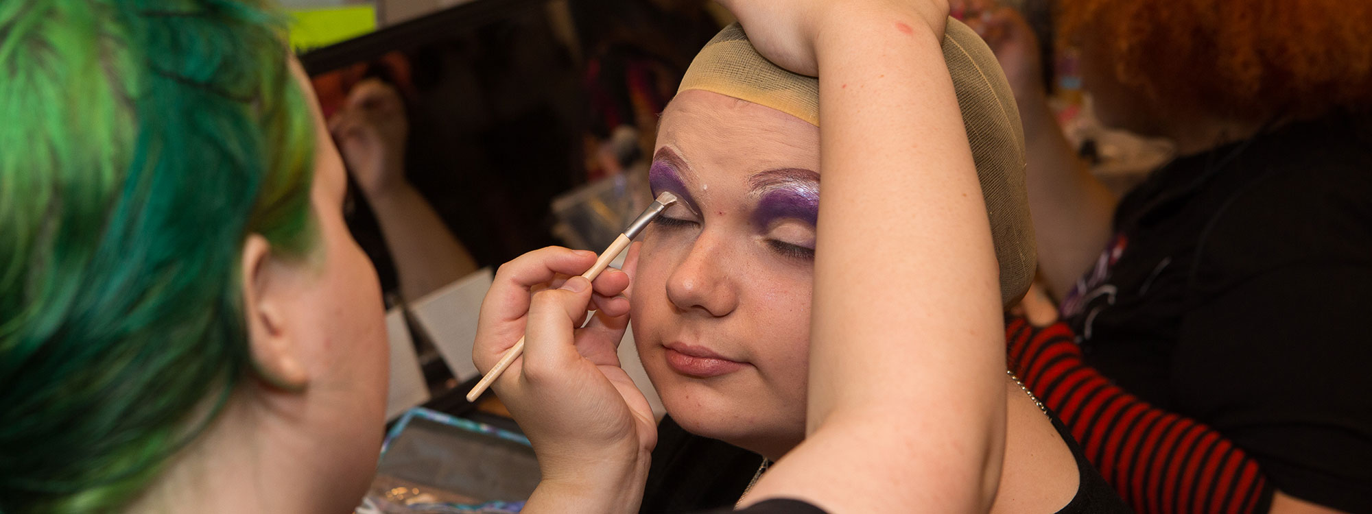 A teen having make-up applied to her face.