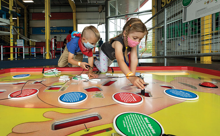 2 children playing a giant-sized version of the game operation.