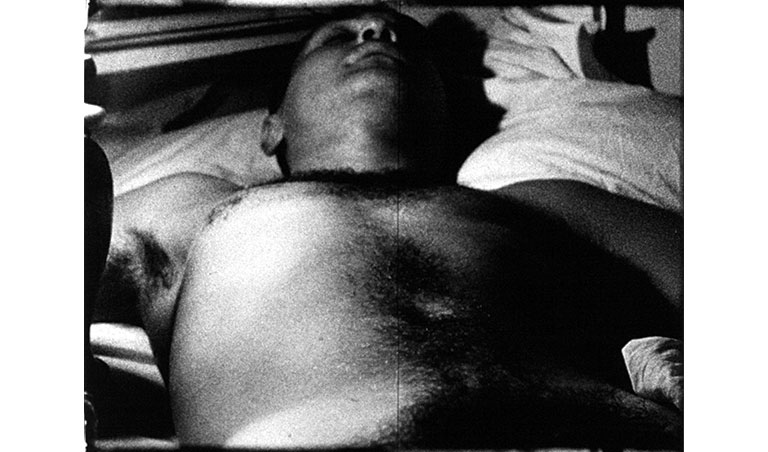 Still image from a black and white film of a man sleeping