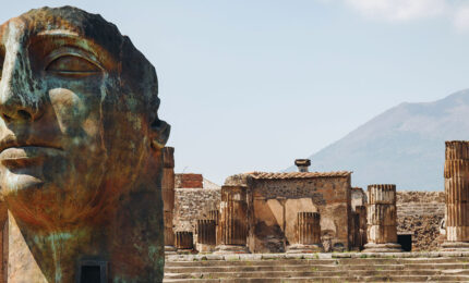 A few of a city ruins with a large sculpture of a human face in the foreground