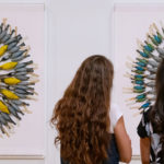 @ young women looking at a museum installatio of birds set in large circular formation