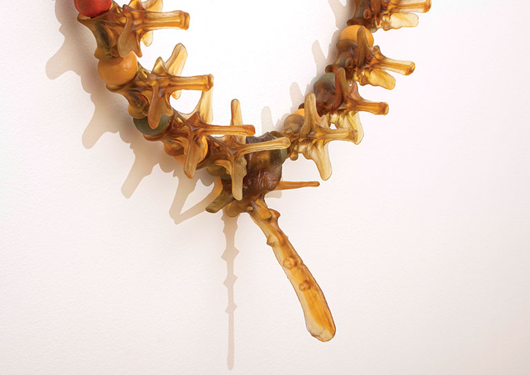 A detail view of a glass necklace resembling the vertebra of a dinosaur