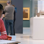 A Black teenager drawing in the art museum
