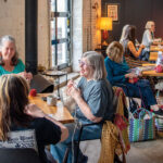 a group of woman crocheting in a local restaurant using colorful yarn