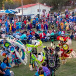 A vibrant gathering with people in colorful traditional attire, dancing and celebrating at a lively outdoor event.
