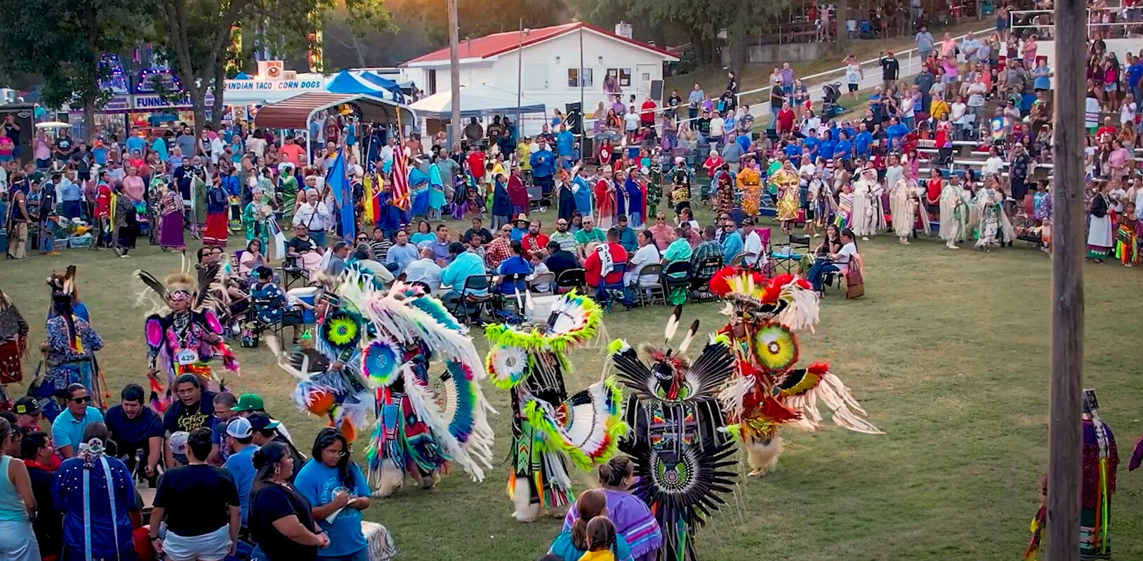 A vibrant gathering with people in colorful traditional attire, dancing and celebrating at a lively outdoor event.