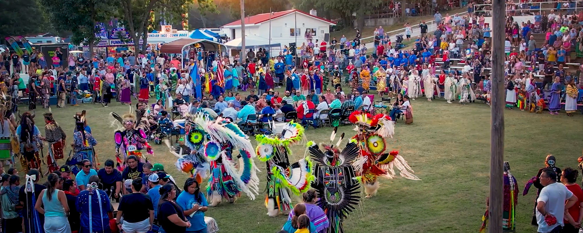 A vibrant gathering with people in colorful traditional attire, dancing and celebrating at a lively outdoor event.