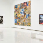 A bright art gallery featuring diverse artworks on white walls, including abstract and nature-themed pieces.