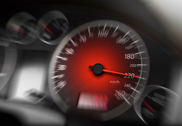 A close-up of a car speedometer shows the needle at 220 km/h. The image conveys speed and intensity, with a blurred background enhancing motion.