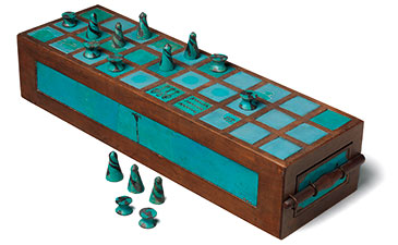 Ancient wooden board game with turquoise squares and metal cone game pieces. Some pieces are on the board, others are beside it. Calm, historical feel.