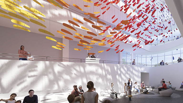 Spacious atrium with colorful, suspended yellow and red art installation. People sit and stand in soft light, creating a calm, interactive atmosphere.