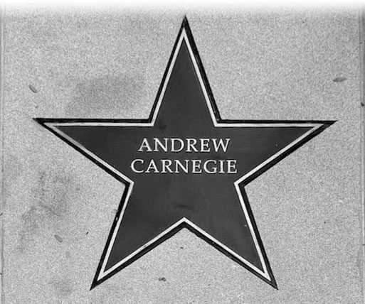 A grayscale image of a star engraved on a sidewalk, featuring the name "Andrew Carnegie" in bold letters. The tone is respectful and commemorative.