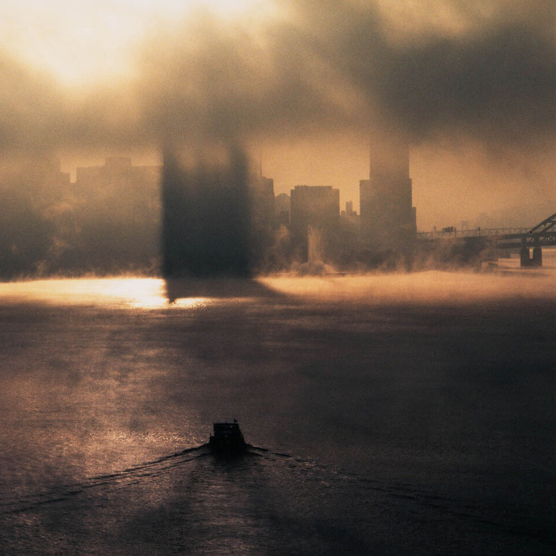 a foggy sunrise over pittsburgh with a boat in the foreground